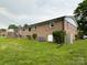 Brick home's spacious backyard with green lawn, utility equipment, and mature trees at 404 Kings Dr # 7, Cherryville, NC 28021