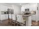 Modern kitchen island featuring bar seating, stainless appliances, and a view into the dining and living area at 446 Misty Law Ln, Clover, SC 29710