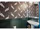 Stylish half bath features a pedestal sink, dark wainscoting and heron-themed wallpaper at 614 West End Dr, Charlotte, NC 28208