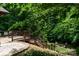 View of backyard featuring the upper level wood deck, patio area, and fire pit surrounded by mature trees at 6398 Winding Creek Ln, Denver, NC 28037
