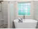 Bright bathroom featuring soaking tub, standalone shower, and a large window with glass blocks at 6398 Winding Creek Ln, Denver, NC 28037