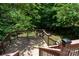 Upper level wood deck with stairs leading down to a fire pit and seating area surrounded by lush trees at 6398 Winding Creek Ln, Denver, NC 28037
