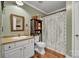 Well-lit bathroom with stylish vanity, wooden floors, and decorative mirror and a shower with a curtain at 725 Hunters Ridge Rd, Taylorsville, NC 28681