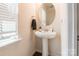 Elegant pedestal sink bathroom with a round mirror, modern fixtures, and neutral tones at 7711 Kelburn Ln, Charlotte, NC 28273