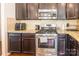 Stainless steel oven and microwave with dark cabinets and a granite countertop, tiled backsplash, and hardwood flooring at 7711 Kelburn Ln, Charlotte, NC 28273