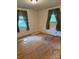 Empty bedroom featuring original wood floors, two windows, and decorative curtains at 910 Absher Rd, Statesville, NC 28625