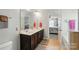 Well-lit bathroom featuring double sinks, a large mirror, tile flooring, and a view into the primary bedroom at 9301 Swimming Dr, Harrisburg, NC 28075