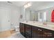 Well-lit bathroom featuring double sinks, a large mirror, tile flooring, and a separate toilet area at 9301 Swimming Dr, Harrisburg, NC 28075