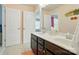 Bathroom with dual sinks, dark cabinets, and a large mirror alongside two doorways at 9301 Swimming Dr, Harrisburg, NC 28075