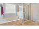 Well-lit bathroom featuring a soaking tub, glass-enclosed shower, tile flooring, and neutral paint at 9301 Swimming Dr, Harrisburg, NC 28075
