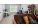 Comfortable living room featuring neutral walls and carpet, reading chairs, desk, shelving, and large window at 9301 Swimming Dr, Harrisburg, NC 28075