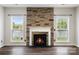 Cozy living room featuring a stone fireplace, hardwood floors, and windows overlooking the backyard at 9647 Laurie Nw Ave, Concord, NC 28027