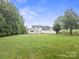 Large, green backyard features the house, outbuilding, and a well-maintained lawn at 10749 Kingsview Dr, Davidson, NC 28036