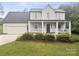 Inviting two-story home featuring a charming covered front porch, attached garage, and verdant landscaping at 10749 Kingsview Dr, Davidson, NC 28036