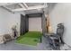 Garage converted into a golf simulation room with turf, screen, golf clubs, and comfortable seating at 11333 Preservation Ln, Charlotte, NC 28278
