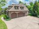 Three-car garage with a large concrete driveway, set against a backdrop of mature trees and greenery at 1260 Rittenhouse Ln, Rock Hill, SC 29732