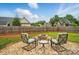 Chairs sit on a stone patio surrounding a firepit in a fenced backyard with green grass at 129 Daniel Efird Dr, Mount Holly, NC 28120