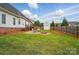A spacious, fenced backyard with a detached garage, wooden deck, and a stone fire pit area at 129 Daniel Efird Dr, Mount Holly, NC 28120