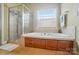 Bright bathroom featuring a walk-in shower, soaking tub, tiled surround, and storage cabinets at 129 Daniel Efird Dr, Mount Holly, NC 28120