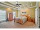 Serene main bedroom featuring tray ceiling, ceiling fan, plush carpet, and ample closet space at 129 Daniel Efird Dr, Mount Holly, NC 28120