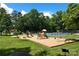 A well-maintained community playground with swings, slides, and climbing structures surrounded by lush trees and greenery at 13430 Norseman Ln, Huntersville, NC 28078