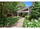 Inviting covered backyard patio with stone accents and comfortable seating, surrounded by lush greenery at 15247 Prescott Hill Ave, Charlotte, NC 28277