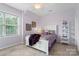 Bright bedroom with a large window, plush carpet, and elegant white furniture and purple accents at 15247 Prescott Hill Ave, Charlotte, NC 28277
