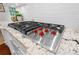 Close-up of the Wolf gas cooktop with a stainless steel finish and red knobs at 15247 Prescott Hill Ave, Charlotte, NC 28277