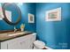 Stylish powder room with blue walls, a granite countertop vanity, and decorative mirror at 15247 Prescott Hill Ave, Charlotte, NC 28277