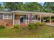Charming brick home with a cozy covered porch and an American flag, surrounded by lush greenery at 157 E Meadowview Dr, Statesville, NC 28625