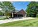 Brick two-car garage with black doors, surrounded by lush landscaping and a well-maintained lawn at 201 Vanderbilt Blvd, Locust, NC 28097
