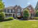 Stately two-story brick home with a covered front porch, manicured lawn, and mature landscaping at 2301 Keara Way, Charlotte, NC 28270