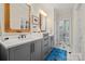 Beautiful bathroom with double vanity, gray cabinets, and unique gold trimmed mirrors at 2329 Club Rd, Charlotte, NC 28205
