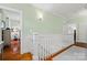 Bright hallway with hardwood floors, white wainscoting, and staircase with white railing at 2329 Club Rd, Charlotte, NC 28205