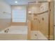 Bathroom featuring tiled shower with glass door and separate soaking tub near a bright window at 3022 Burnello Ct, Iron Station, NC 28080