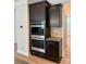 A kitchen with stainless steel double ovens surrounded by dark cabinets and light colored backsplash at 3022 Burnello Ct, Iron Station, NC 28080