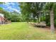 Expansive backyard with lush green grass, mature trees, a deck, and a storage shed at 3049 Stablegate Dr, Gastonia, NC 28052