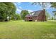 View of brick home's backyard, featuring a spacious lawn, deck, and a full fence at 3049 Stablegate Dr, Gastonia, NC 28052