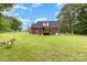 Backyard view featuring green grass, a brick house, mature trees, and a full fence at 3049 Stablegate Dr, Gastonia, NC 28052