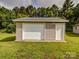 Single-car garage with traditional white door and siding, set on green lawn with mature trees at 4111 Jenkins Rd, Marshville, NC 28103