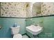A vintage bathroom boasts pastel tile, floral wallpaper, and classic fixtures at 4220 Castlewood Rd, Charlotte, NC 28209