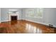 Living room featuring hardwood floors, fireplace, and a bright window with white plantation shutters at 4220 Castlewood Rd, Charlotte, NC 28209