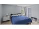 This is a bedroom with neutral decor, large window, bedside table and bench at 4531 Dalbeth St, Charlotte, NC 28213