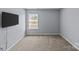 Spacious bedroom featuring an air vent, carpet, a window with blinds, and a wall-mounted TV at 4531 Dalbeth St, Charlotte, NC 28213