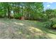 Lush backyard featuring a small storage shed, grass, mature trees, and partial fence line, adding privacy and functionality at 4619 Glasgow Ct, Gastonia, NC 28056