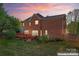 Expansive backyard features a deck, patio, manicured landscaping, and beautiful brick home enhanced by a vibrant sunset at 4619 Glasgow Ct, Gastonia, NC 28056