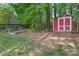 Lush backyard featuring a small storage shed, grass, mature trees, and partial fence line, adding privacy and functionality at 4619 Glasgow Ct, Gastonia, NC 28056
