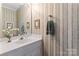Half bathroom offers striped wallpaper, framed art, and a white sink vanity, perfect for guests at 4619 Glasgow Ct, Gastonia, NC 28056