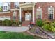 Charming front porch of brick home featuring landscaped garden, potted plants and white front door at 4619 Glasgow Ct, Gastonia, NC 28056