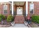 Charming front porch of brick home featuring landscaped garden, potted plants and white front door at 4619 Glasgow Ct, Gastonia, NC 28056
